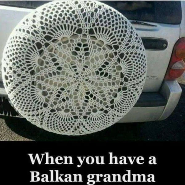 Car spare tire covered in white crocheted doily typical of Balkan grandma crafts.