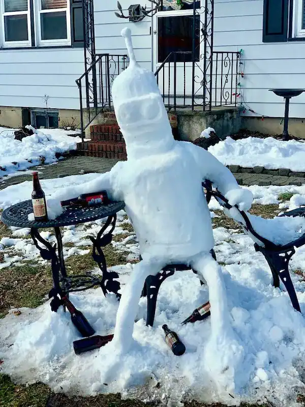 Bender from Futurama snow sculpture sitting with beer bottles.