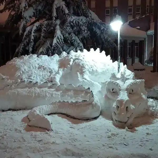Sleeping dragon snow sculpture curled around a street lamp.