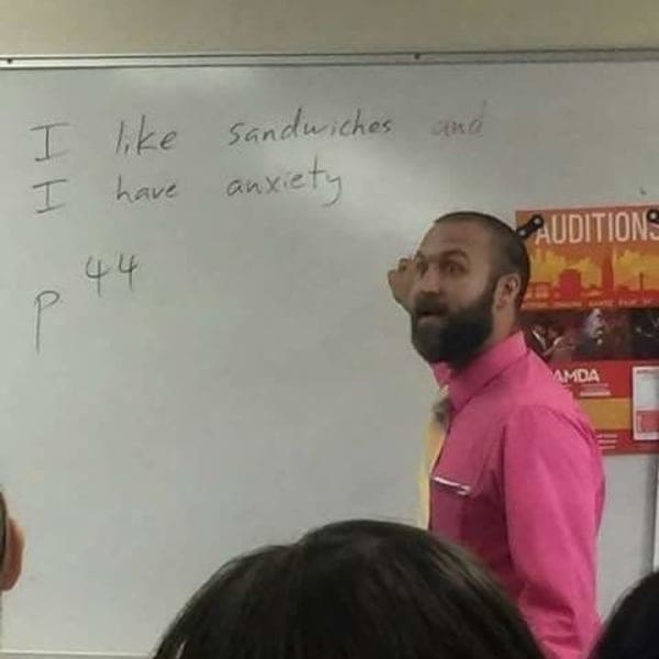 Teacher writing personal facts about sandwiches and anxiety on a whiteboard.