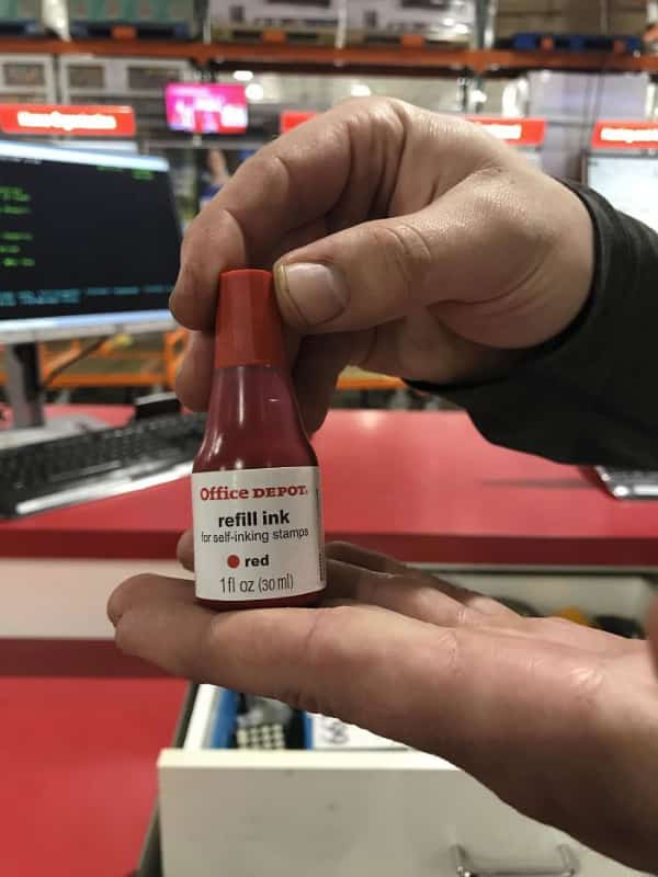 Small red bottle of Office Depot refill ink held in hand resembling hot sauce.