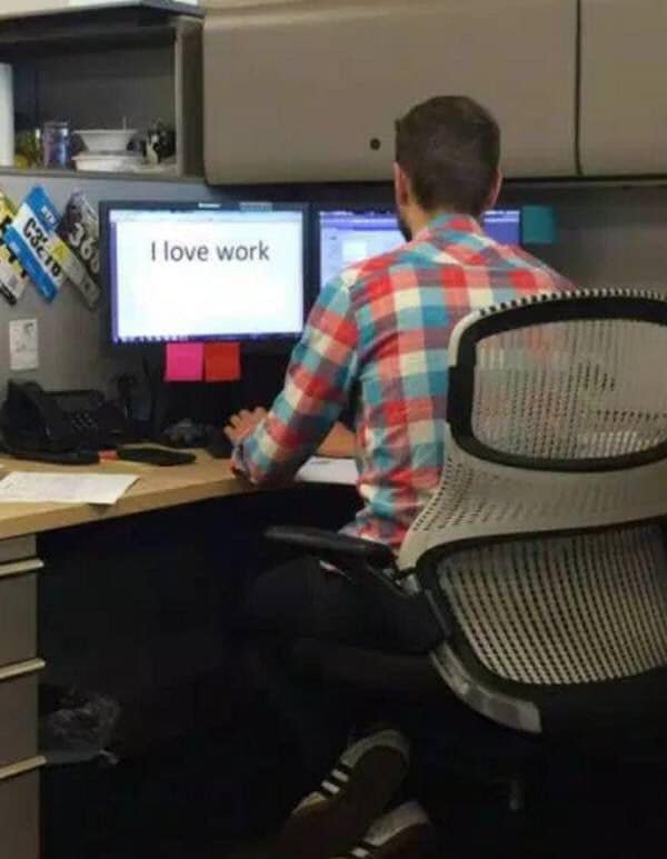 A funny meme showing a man with fingers crossed behind his back while looking at a screen saying I love work.