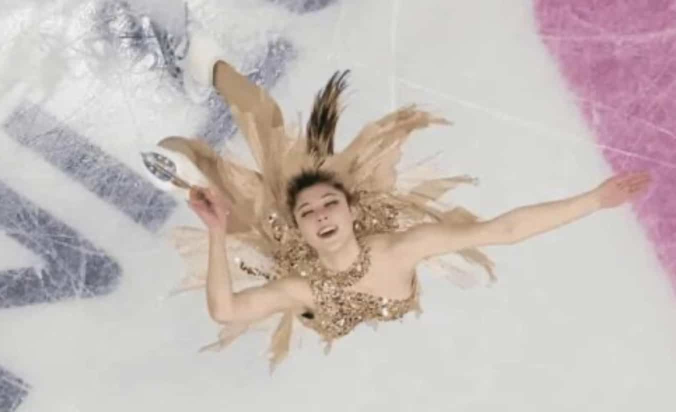 A funny overhead action shot of a figure skater in a gold sequined dress performing on ice.