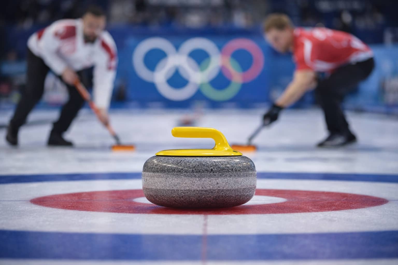 Close-up of a granite curling stone on ice with Olympic curling athletes sweeping in background.