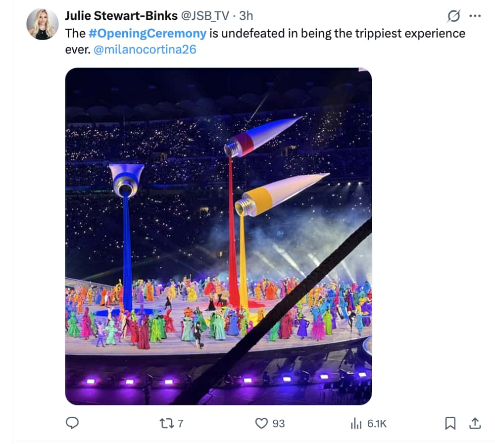 Milan Olympics opening ceremony memes tweet: A wide shot of giant floating paint tubes pouring red, yellow, and blue fabric onto the stadium floor, described as the "trippiest experience ever."