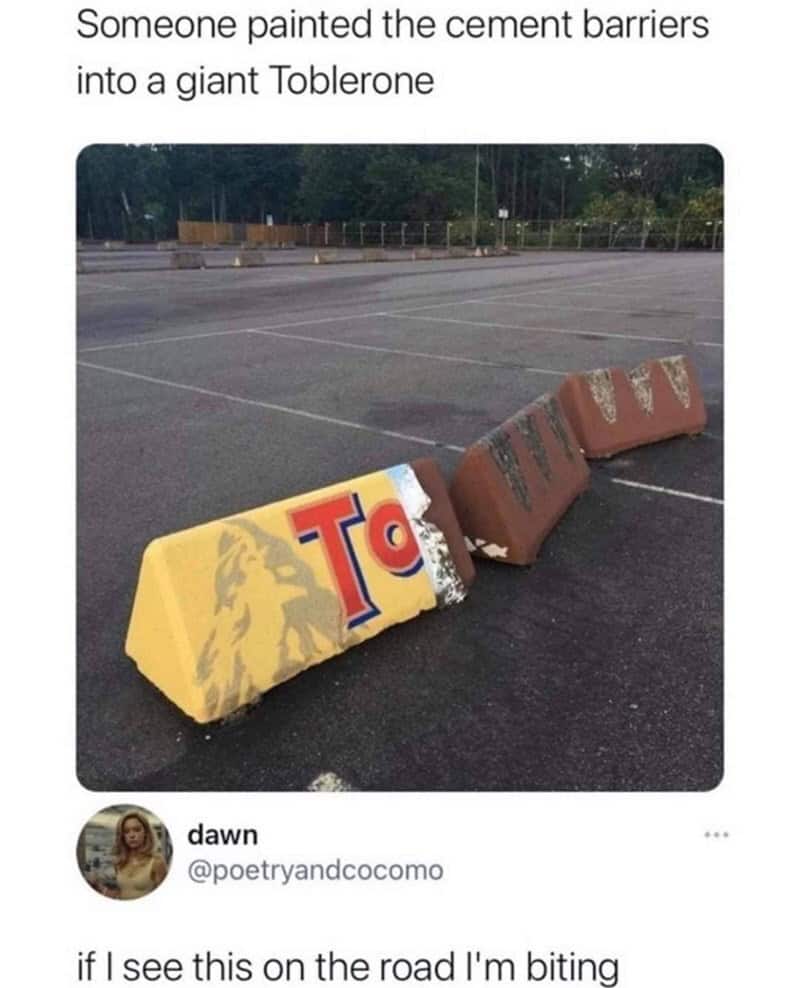 Cement road barriers painted to look like giant Toblerone chocolate bars in a parking lot.
