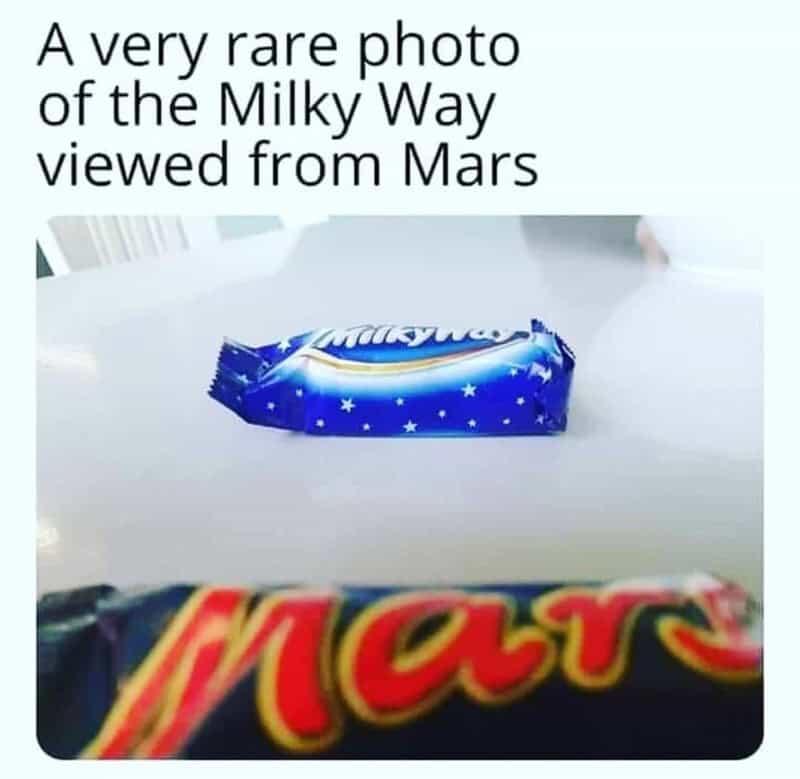 A Milky Way candy bar placed in the background behind a blurry Mars candy bar.