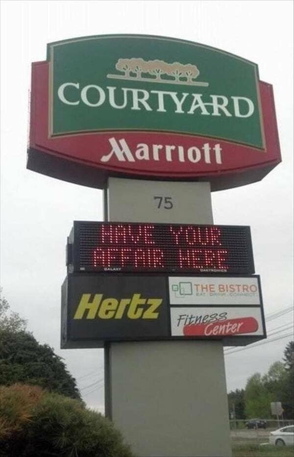 A classic meme photo of a Courtyard Marriott sign with a marquee reading "HAVE YOUR AFFAIR HERE" right above a Hertz logo.