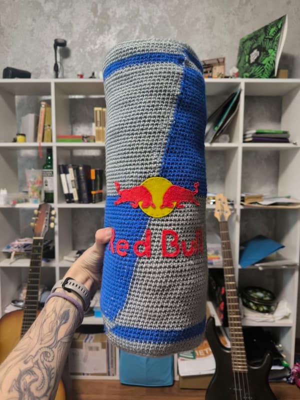 A giant creative knitting project pillow crocheted to look exactly like a can of Red Bull energy drink.