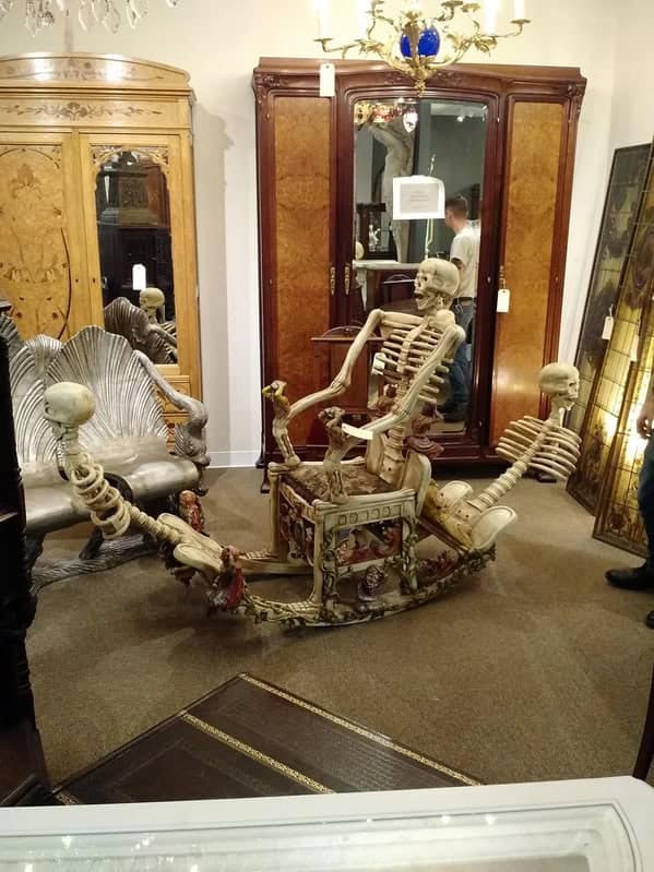 A macabre weird furniture rocking chair constructed entirely from artificial human skeletons, with bones forming the armrests and rockers.
