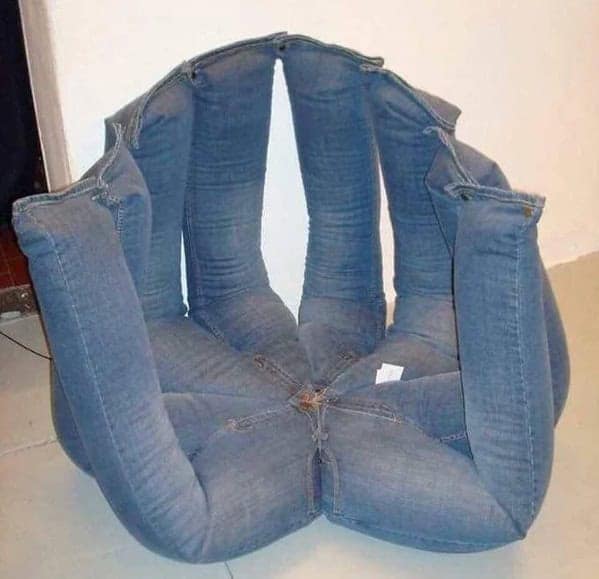 A cursed furniture armchair made from several pairs of blue jeans sewn together in a circle, with the legs of the jeans acting as the chair's back and sides.