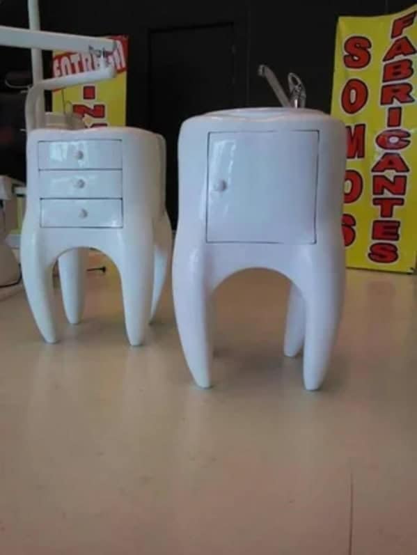 A cursed furniture cabinet shaped like a giant, glossy white molar tooth with a small drawer and cupboard door built into the enamel.