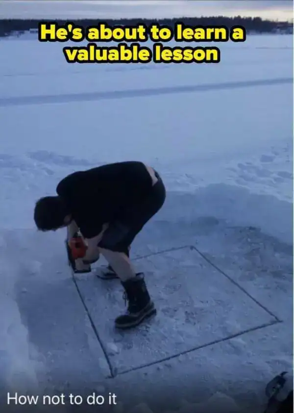 Man using a chainsaw to cut a square in lake ice while standing inside the square.