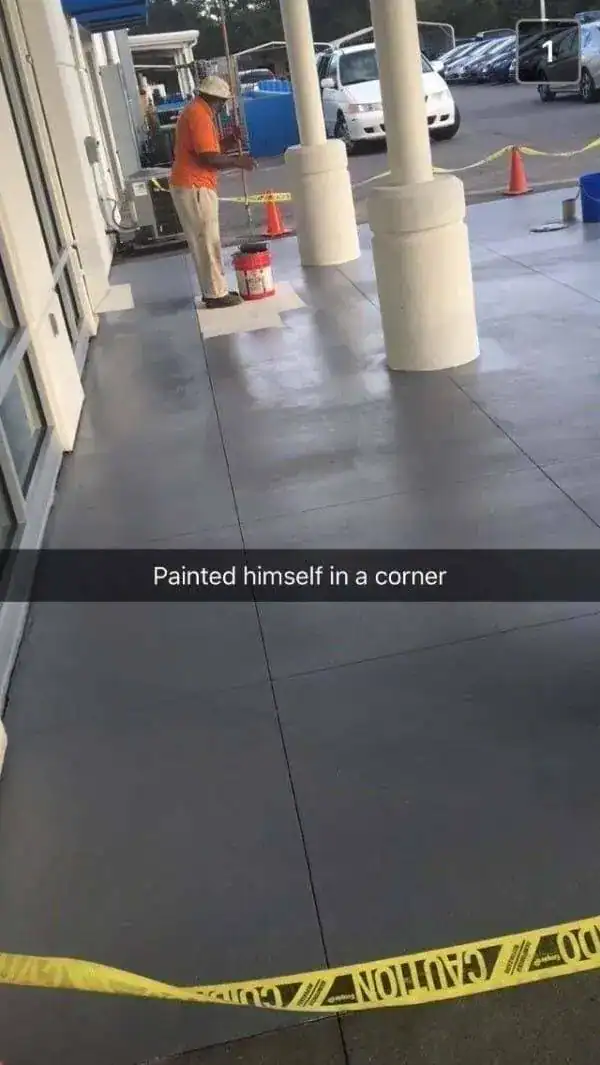 Worker at a car dealership who has accidentally painted the concrete floor into a corner.