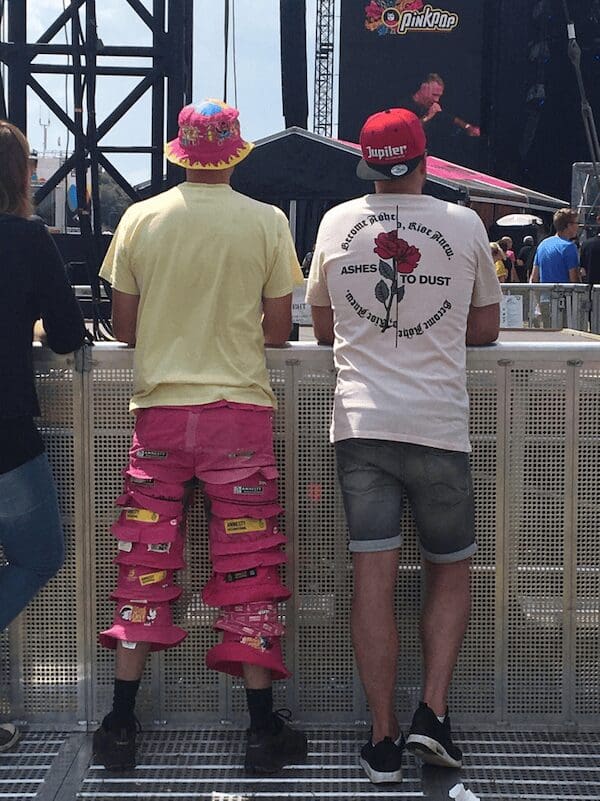 A festival-goer at Pinkpop wearing pants constructed entirely out of stacked pink bucket hats, a creative fashion faux pas.