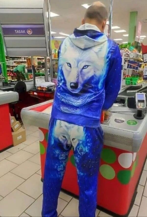 A man in a grocery store wearing a matching blue tracksuit with a giant white wolf face printed on the back and butt, a classic fashion faux pas.