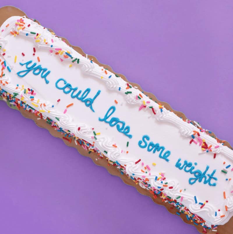A funny cake with a passive-aggressive message written in cursive icing that tells the recipient you could lose some weight.