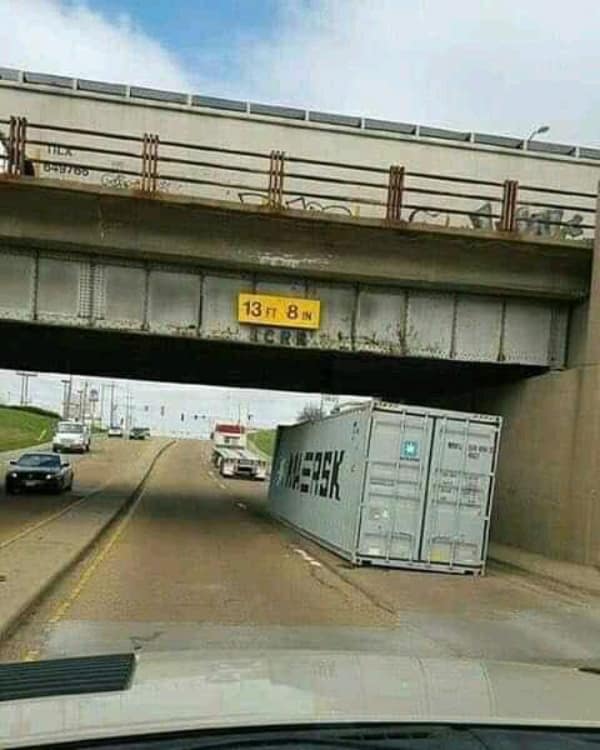 A classic funny fail showing a massive Maersk shipping container that was cleanly scraped off its truck bed by a low 13-foot 8-inch overpass, left completely abandoned on the highway.