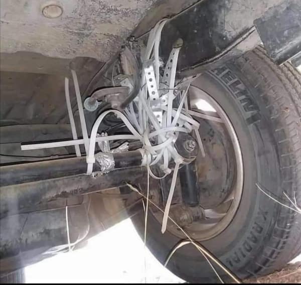 A wildly unsafe DIY repair funny fail capturing a car's entire rear suspension and shock absorber held together by nothing but dozens of plastic white zip ties and sheer willpower.