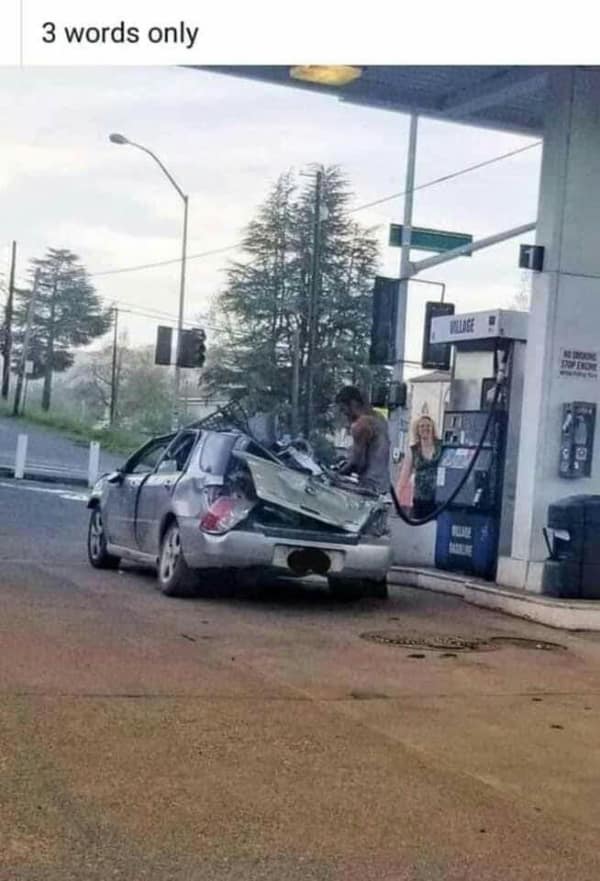 A ridiculous bad day photo showing a man at a gas station casually pumping fuel into a silver car that has its entire rear end violently crushed and compacted into scrap metal.