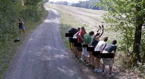 A group of people lined up on the side of a road mooning the camera.