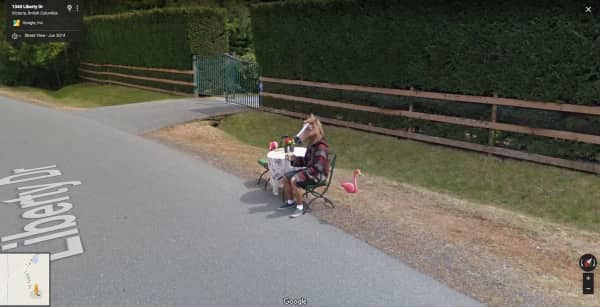 A person in a horse mask sitting at a small table with a pink flamingo.