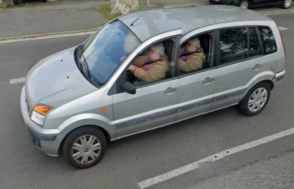 A silver car distorted by a camera glitch to look impossibly long with extra doors.