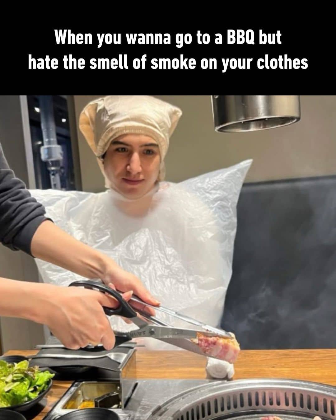 Person wearing a large plastic bag and hairnet to avoid smoke smell at a BBQ.