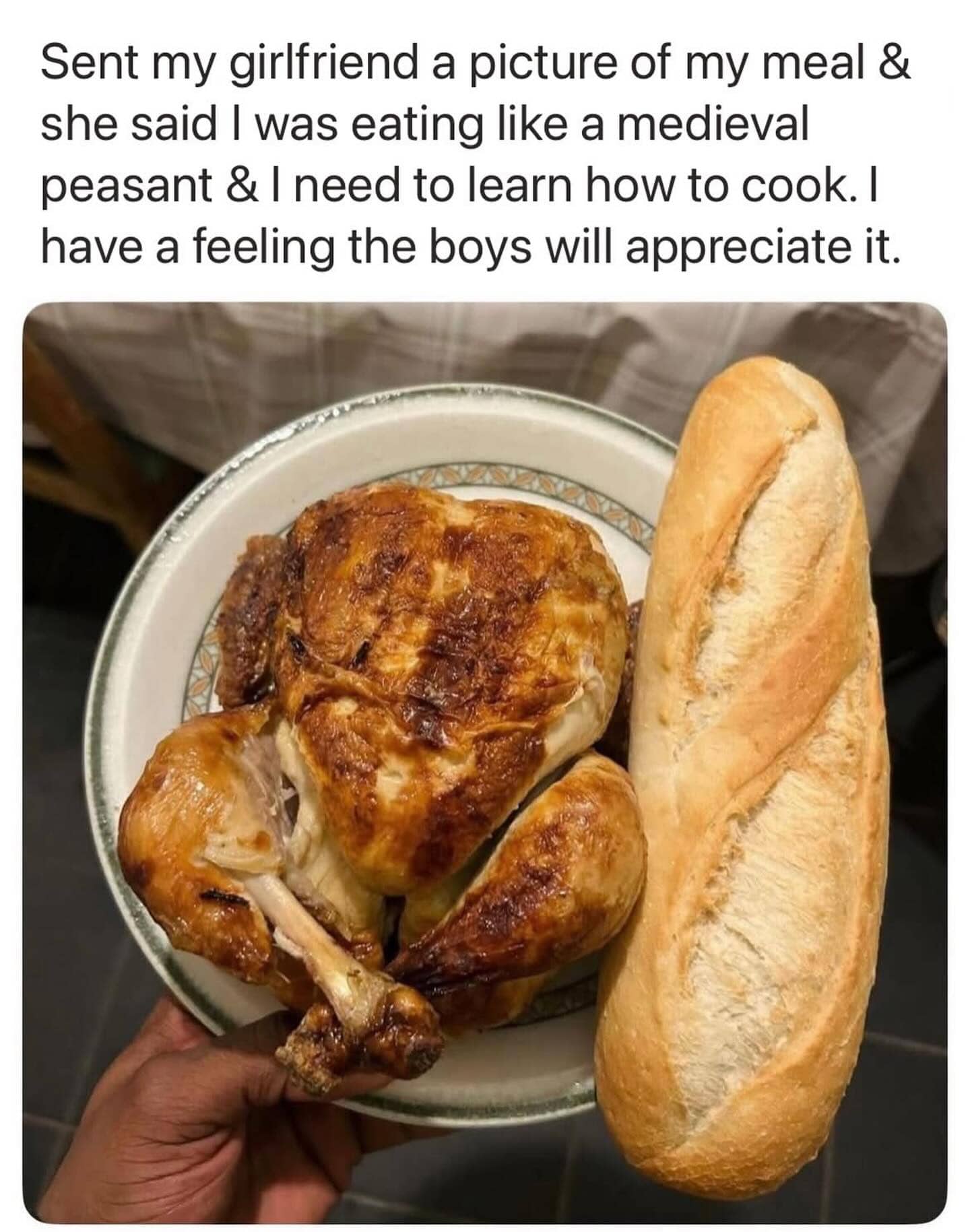 A whole roasted chicken served on a plate next to a large baguette loaf.