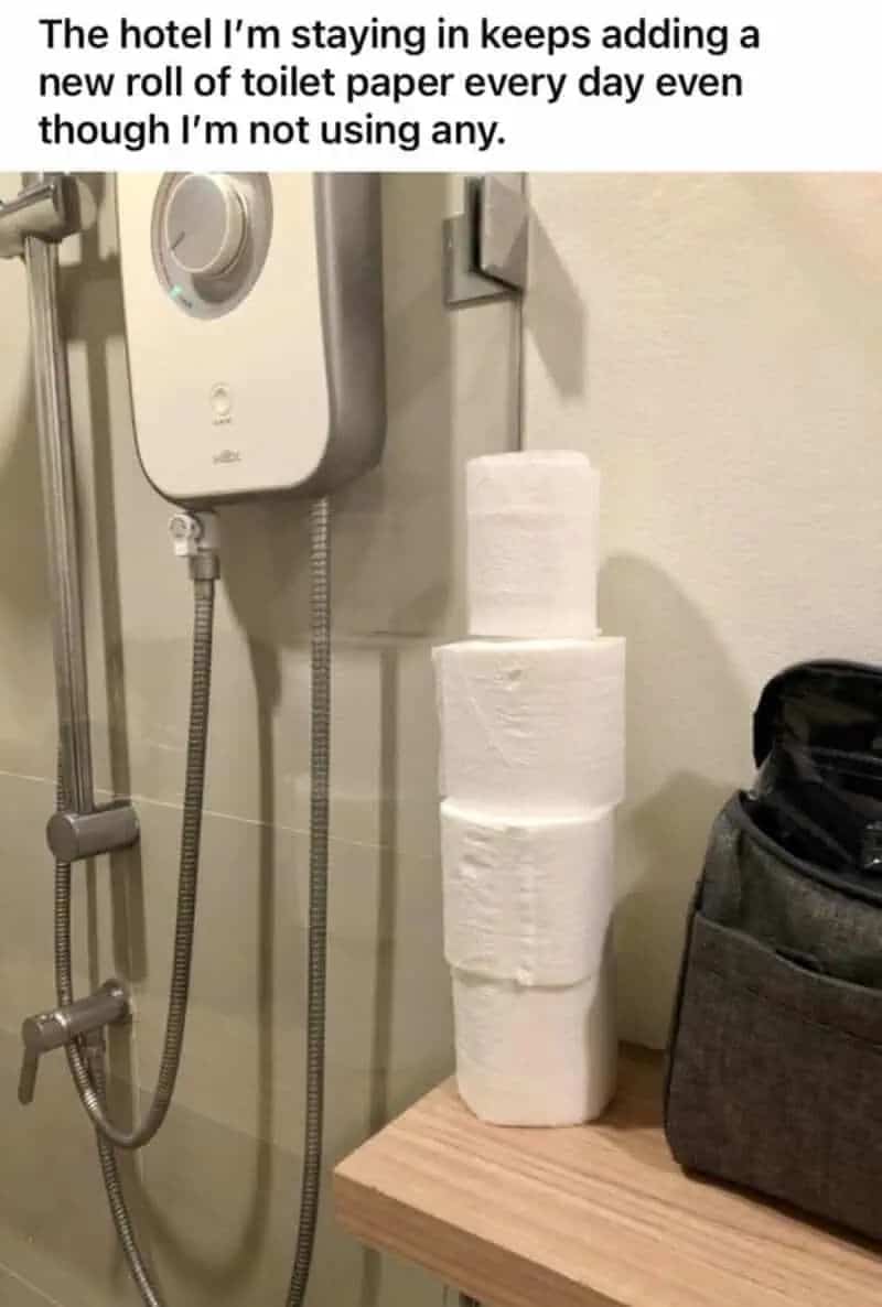 Humorous photo showing a hotel bathroom with a growing stack of unused toilet paper rolls.