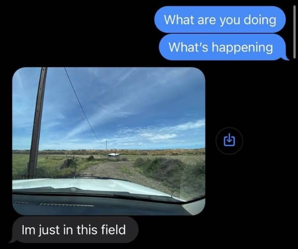 Phone screen showing a confusing text message containing a photo of a dirt road and a field.