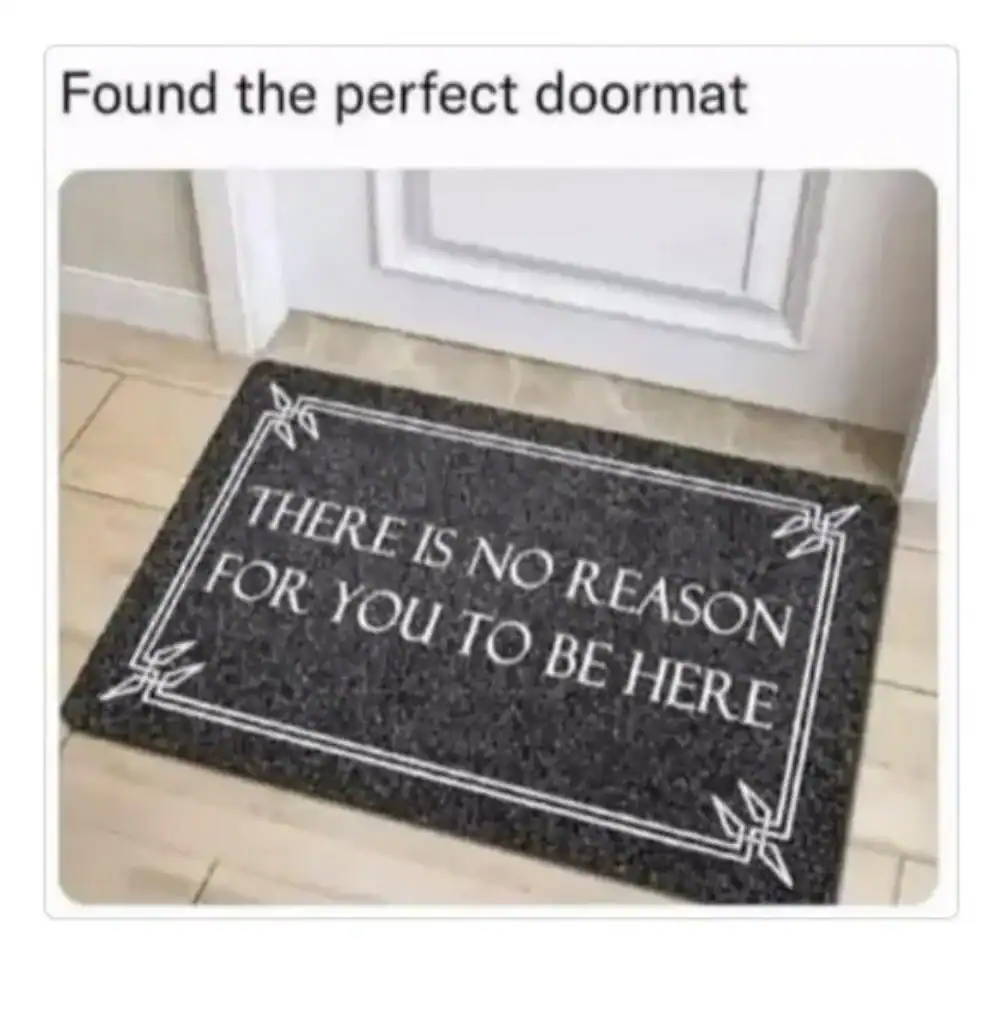 A black doormat with white text that reads, "THERE IS NO REASON FOR YOU TO BE HERE."