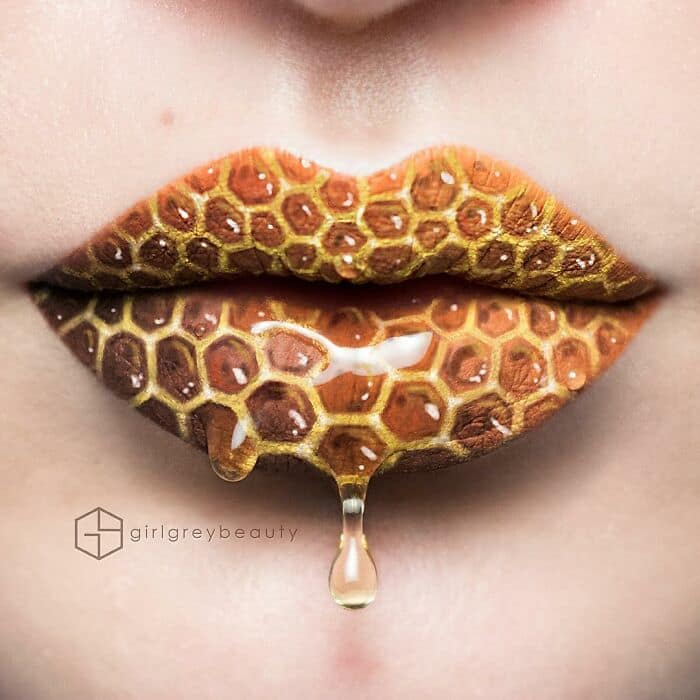 A mouth-watering, hyper-realistic amazing lip art creation featuring a 3D golden honeycomb pattern with a thick drop of honey dripping down the chin, a masterpiece of Andrea Reed lip art.