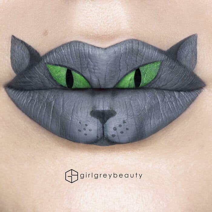 A captivating and slightly spooky amazing lip art illusion turning the mouth into a grey feline face with piercing, vibrant green eyes, a signature optical illusion by Andrea Reed lip art.