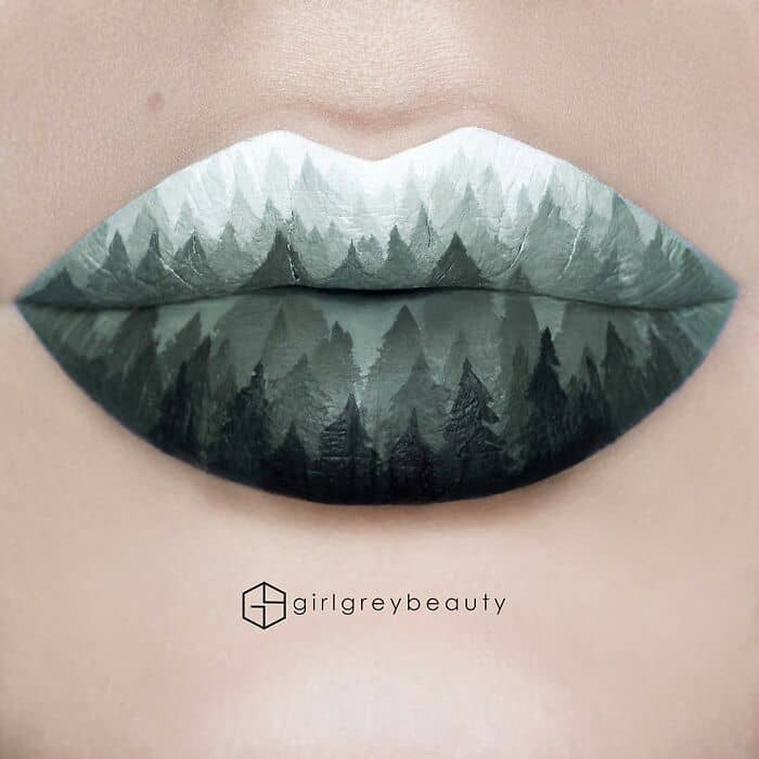 Incredible and amazing lip art depicting a serene, misty forest landscape with intricate silhouettes of layered evergreen trees, showcasing the breathtaking painterly precision of Andrea Reed lip art.