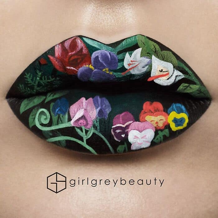 Beautifully detailed and amazing lip art showcasing a delicate, hand-painted floral arrangement of colorful pansies, roses, and green vines over a deep black background in the stunning Andrea Reed lip art aesthetic.