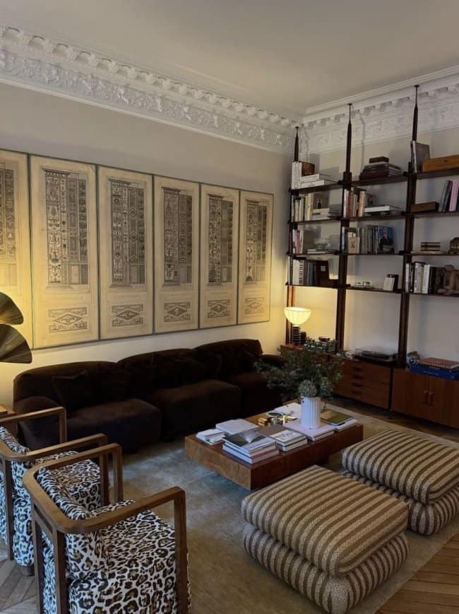 An eclectic awesome home decor living room mixing classic crown molding with industrial shelving, a dark velvet sofa, and bold animal print armchairs.