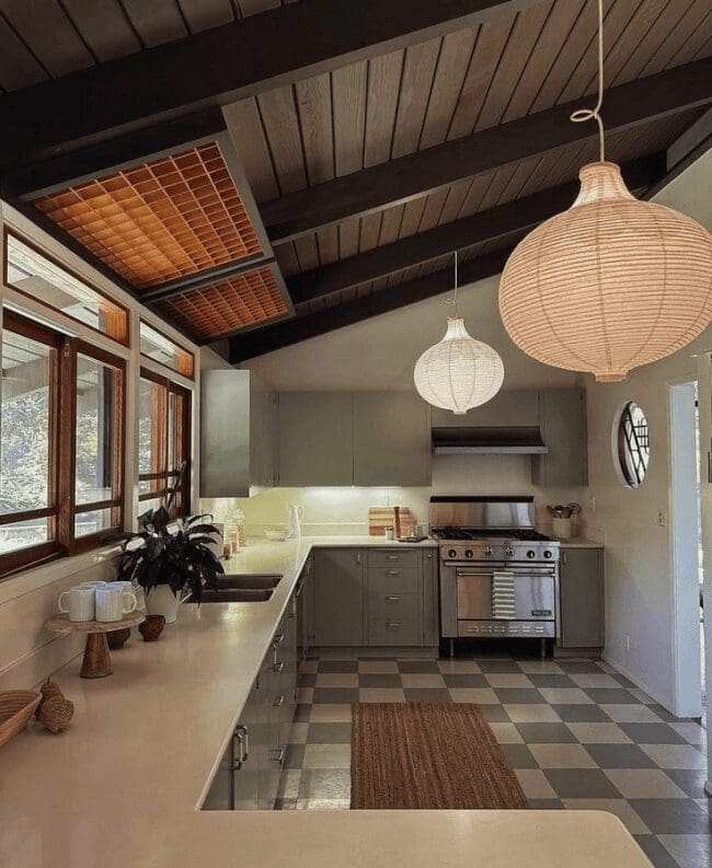 A stylish masculine home decor mid-century modern kitchen featuring a vaulted wood ceiling, checkerboard floors, and oversized paper lantern pendant lights.