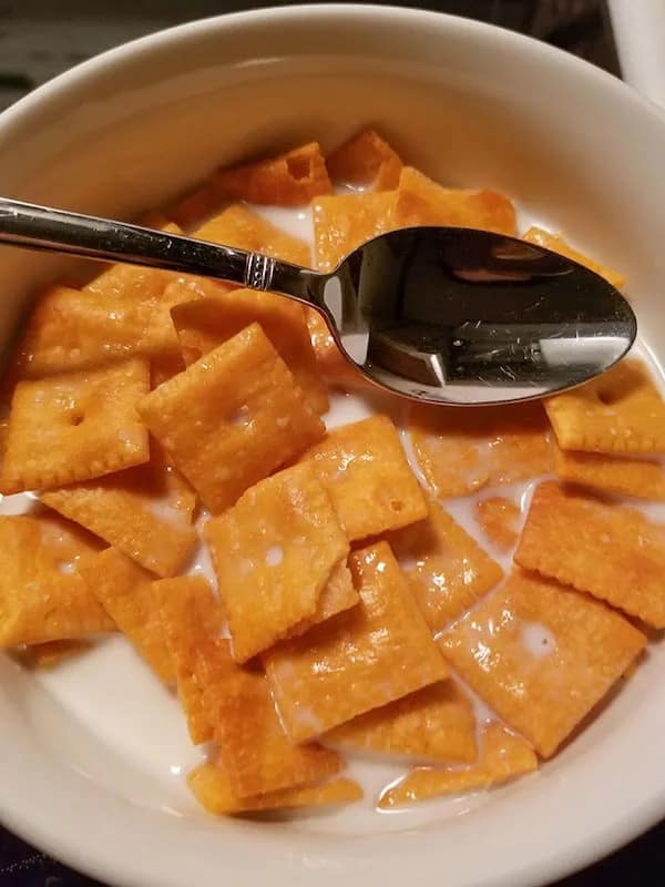 A meme dump photo of a bowl filled with Cheez-It crackers and milk, being eaten with a spoon like cereal.