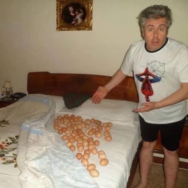 Man in Spider-Man shirt standing next to bed covered in eggs funny meme without context.