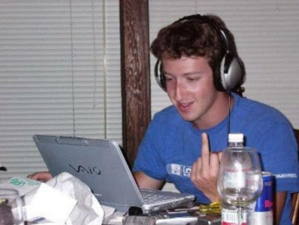 A nerd meme photo of a young Mark Zuckerberg sitting at a laptop flipping off the camera.