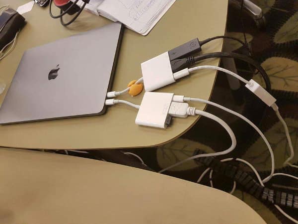 A geeky meme showing an Apple MacBook connected to a chaotic daisy chain of white dongles and adapters.