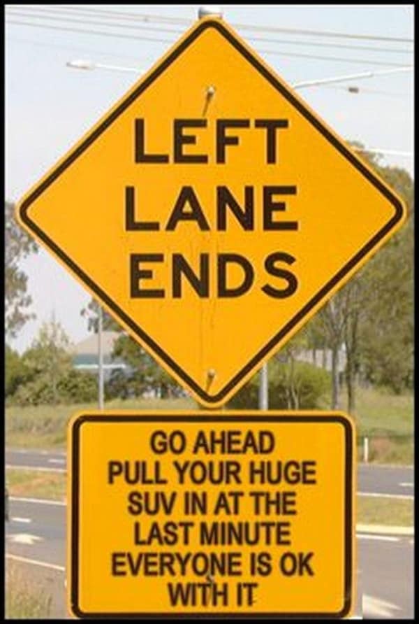 A road rage meme featuring a fake road sign sarcastically telling huge SUVs to pull in at the last minute because "everyone is ok with it."