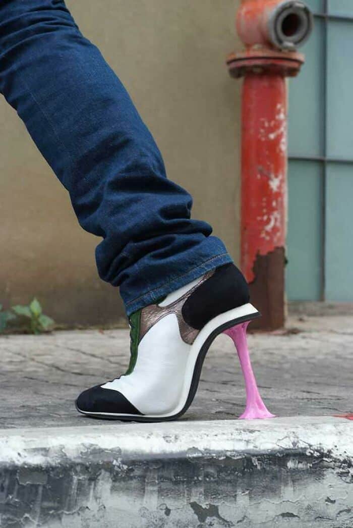 White and black leather dress shoe with a heel made of stretched pink bubblegum stuck to the sidewalk.