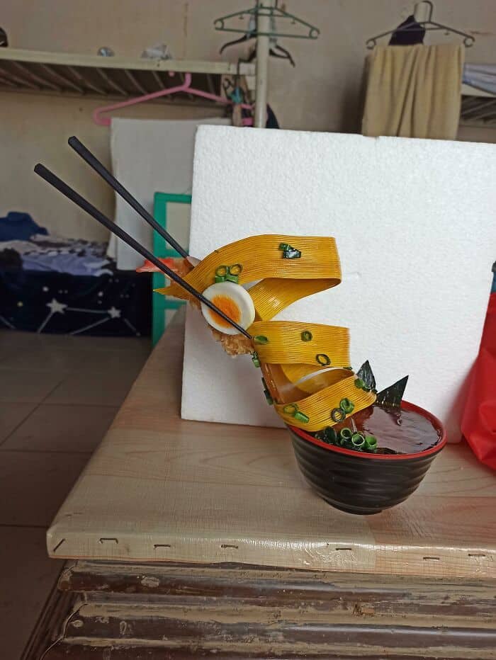 High-heeled shoe designed to look like a bowl of ramen with noodle straps and a boiled egg accent.