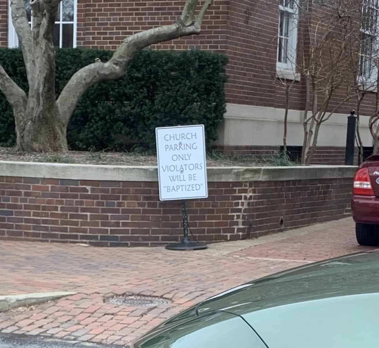 Church parking sign threatening that violators will be baptized in quotation marks.