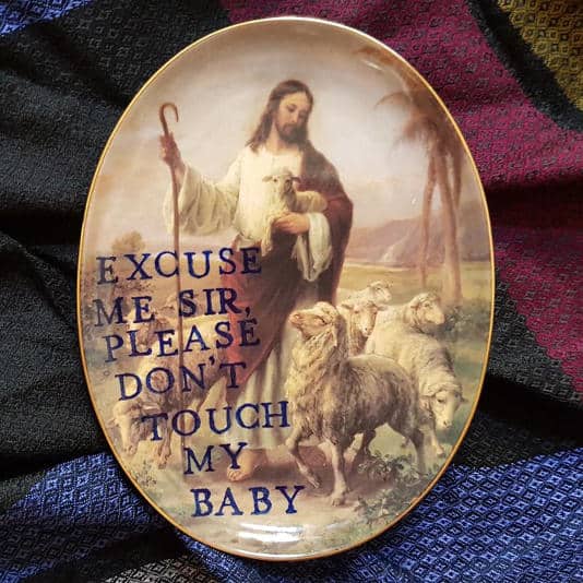 Religious art plate of a shepherd with sheep and text asking sir not to touch his baby.