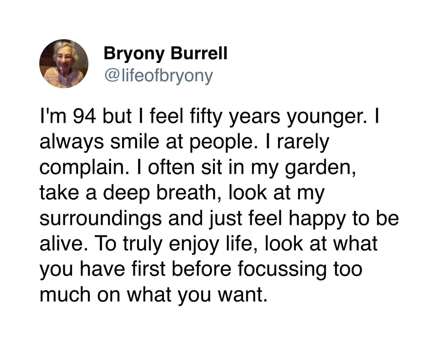 A wholesome tweet from 90 year old sharing wisdom on feeling fifty years younger by smiling, sitting in the garden, and focusing on what you have rather than what you want.