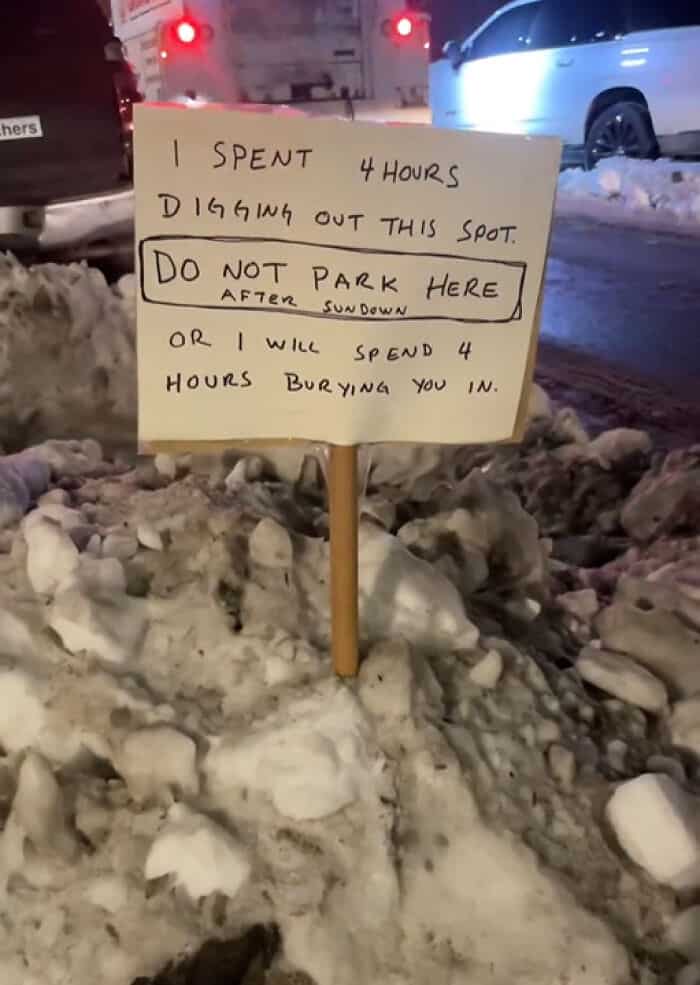 Handwritten sign on a snowbank warning drivers not to park in a four-hour shoveled spot.