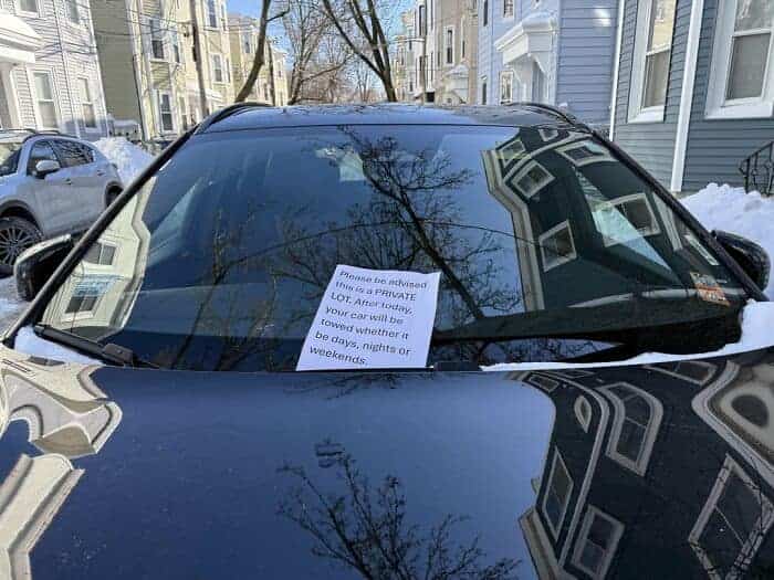 Warning note on a car windshield regarding a private lot and the threat of towing.